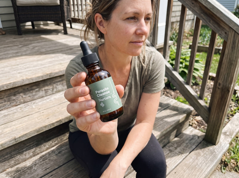 Nurtura customer holding her Parasite Cleanse bottle