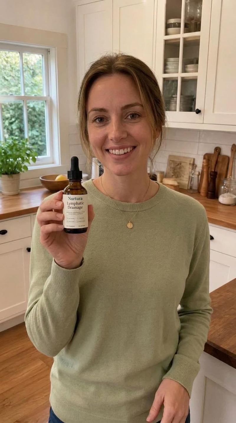 A woman in her kitchen holding a bottle of Nurtura Lymphatic Drainage Drops